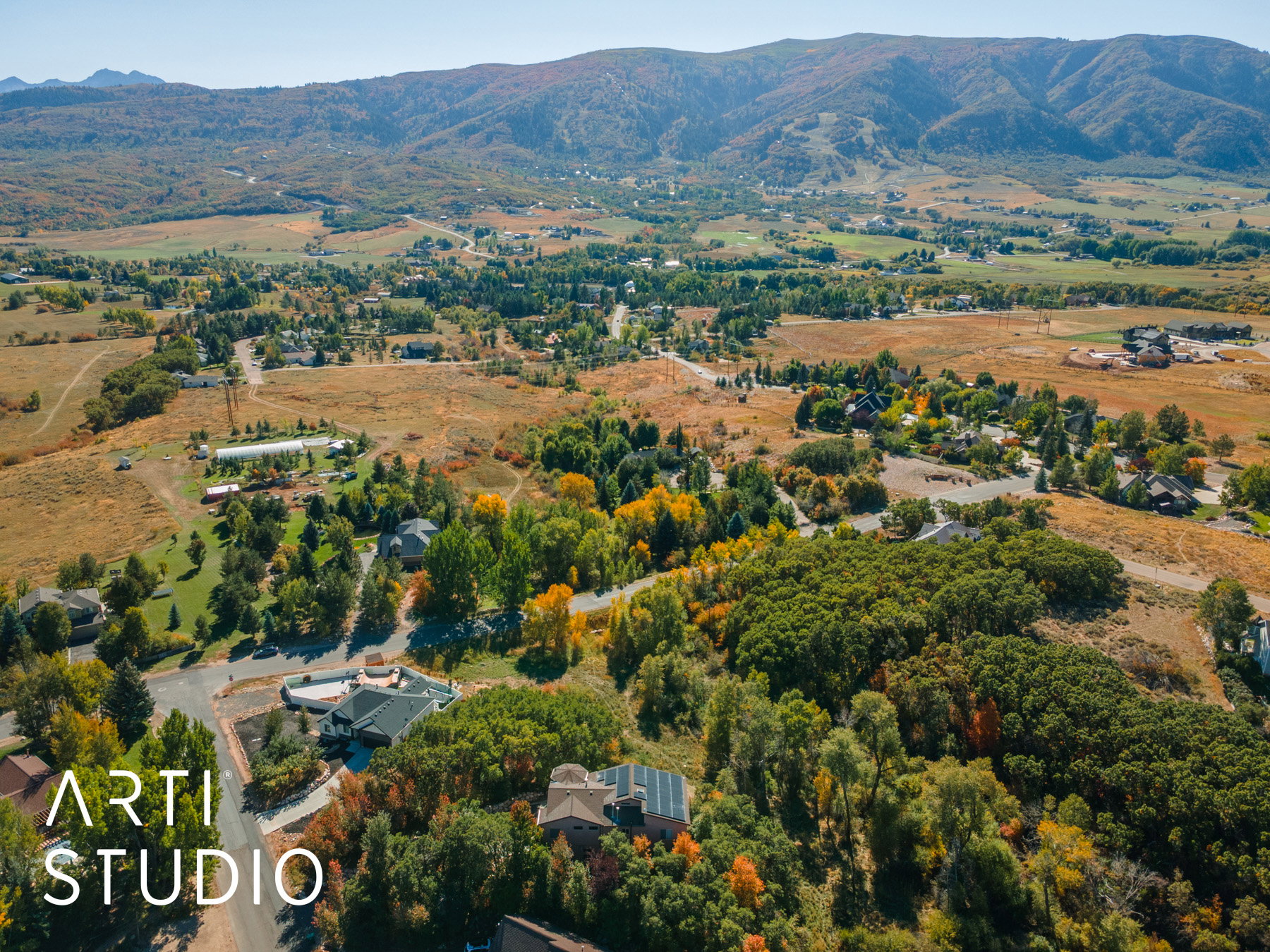 Expansive aerial showcasing a mountainous backdrop, varied topography, and dispersed residential properties