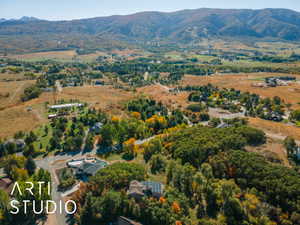 Expansive aerial showcasing a mountainous backdrop, varied topography, and dispersed residential properties