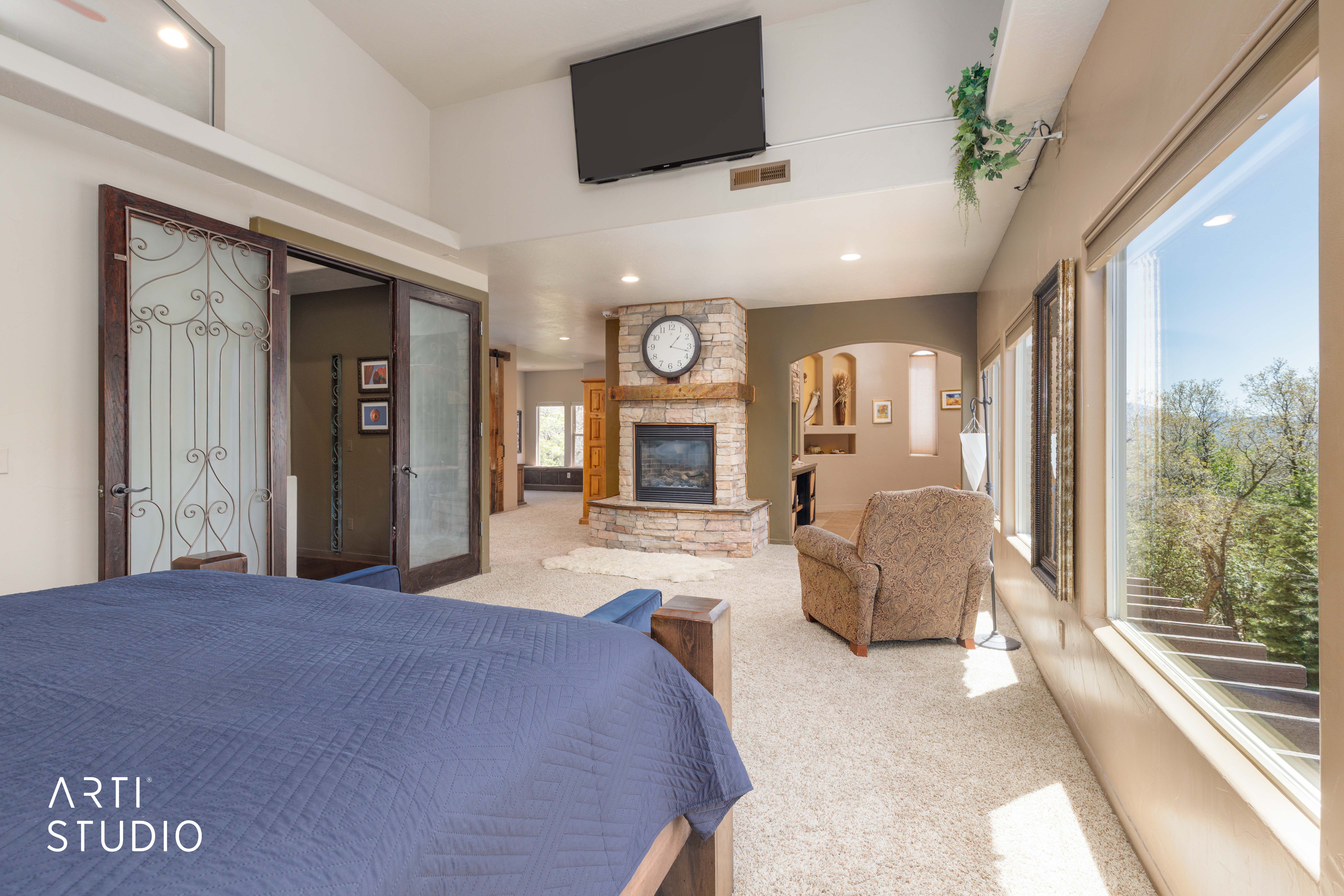 Spacious room featuring vaulted ceilings, a stone fireplace with wood mantel, large windows, and carpet flooring