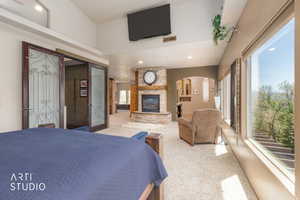 Spacious room featuring vaulted ceilings, a stone fireplace with wood mantel, large windows, and carpet flooring
