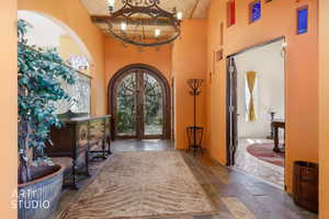 Arched double-door entryway with an overhead chandelier