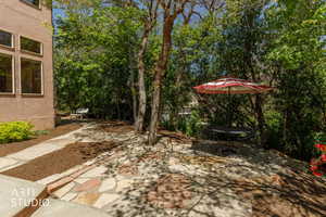 Landscaped outdoor area featuring a flagstone patio, mature trees, mulch ground cover, and a stone pathway