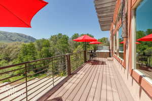 Expansive outdoor deck featuring wood-finish flooring, metal railings, and a built-in spa