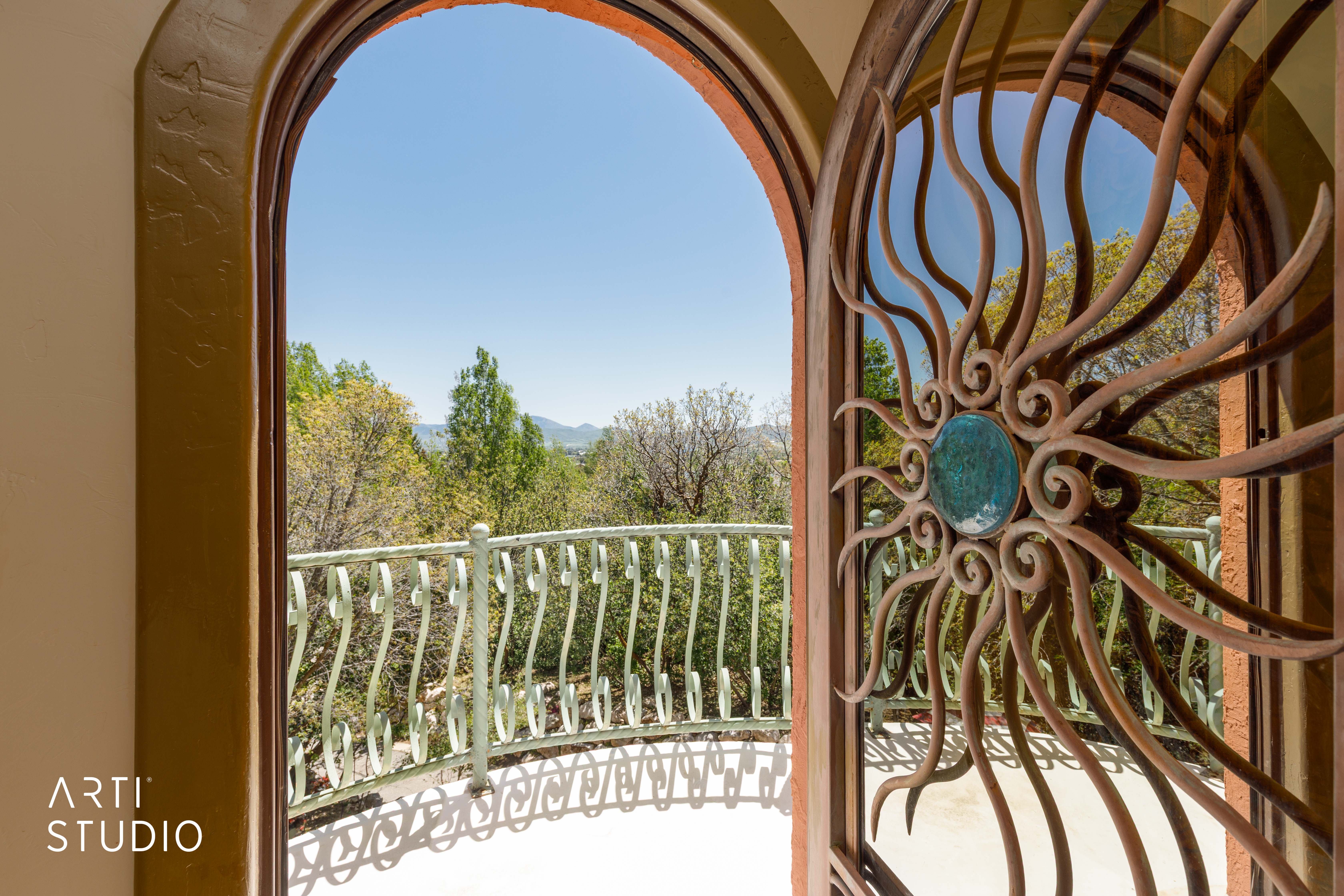Arched doorway featuring a custom copper gate with a central turquoise accent