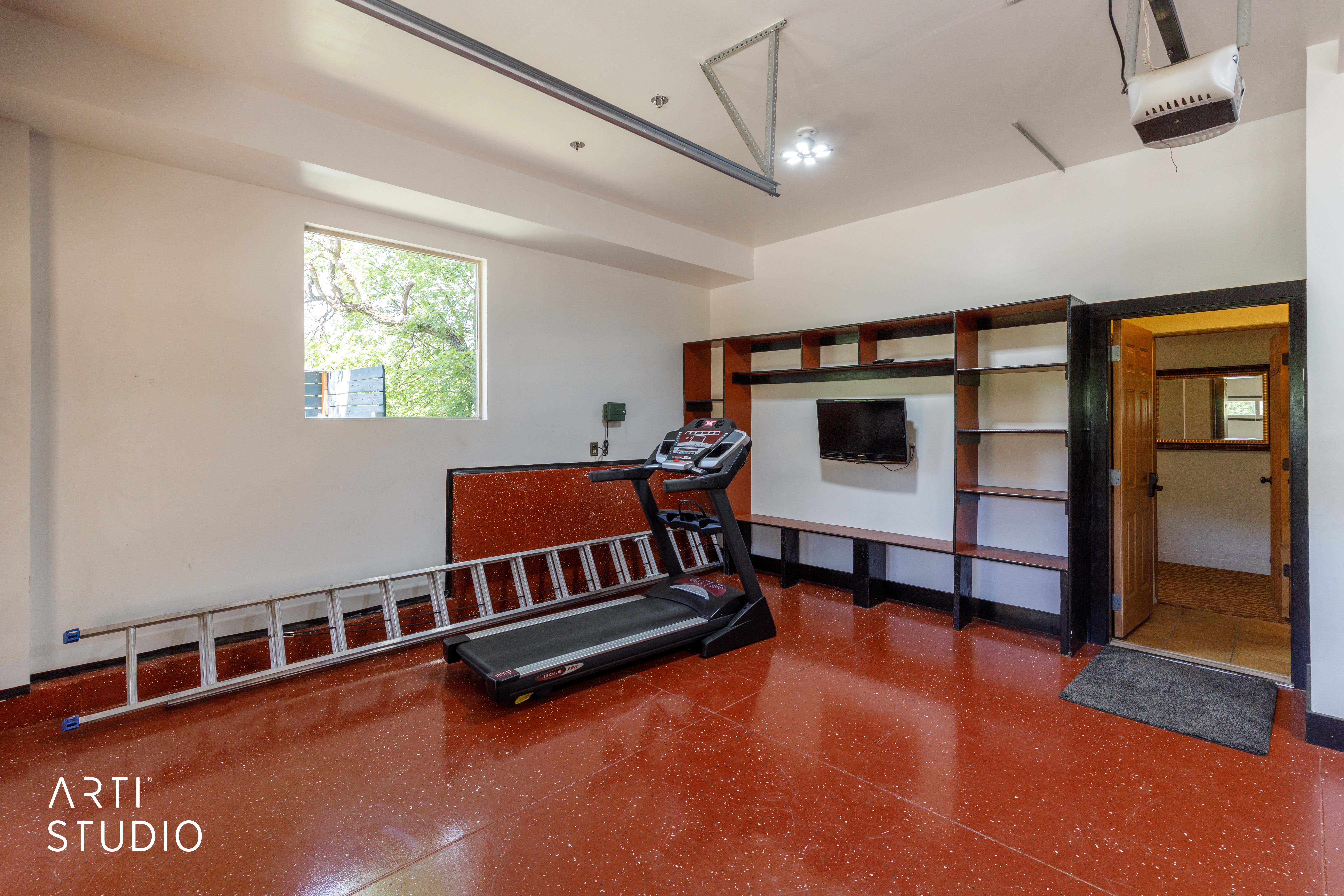 Garage space featuring a red-hued, textured floor and ample built-in shelving