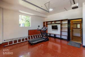 Garage space featuring a red-hued, textured floor and ample built-in shelving