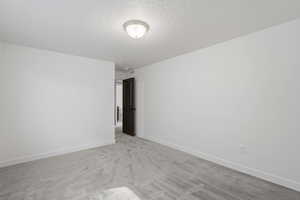 Neutral white walls with matching baseboards, textured ceiling, and a flush mount ceiling light