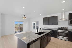 Open-concept kitchen featuring an island with granite countertops and an undermount sink, dark wood-finish cabinetry, stainless steel appliances, and light wood-finish flooring
