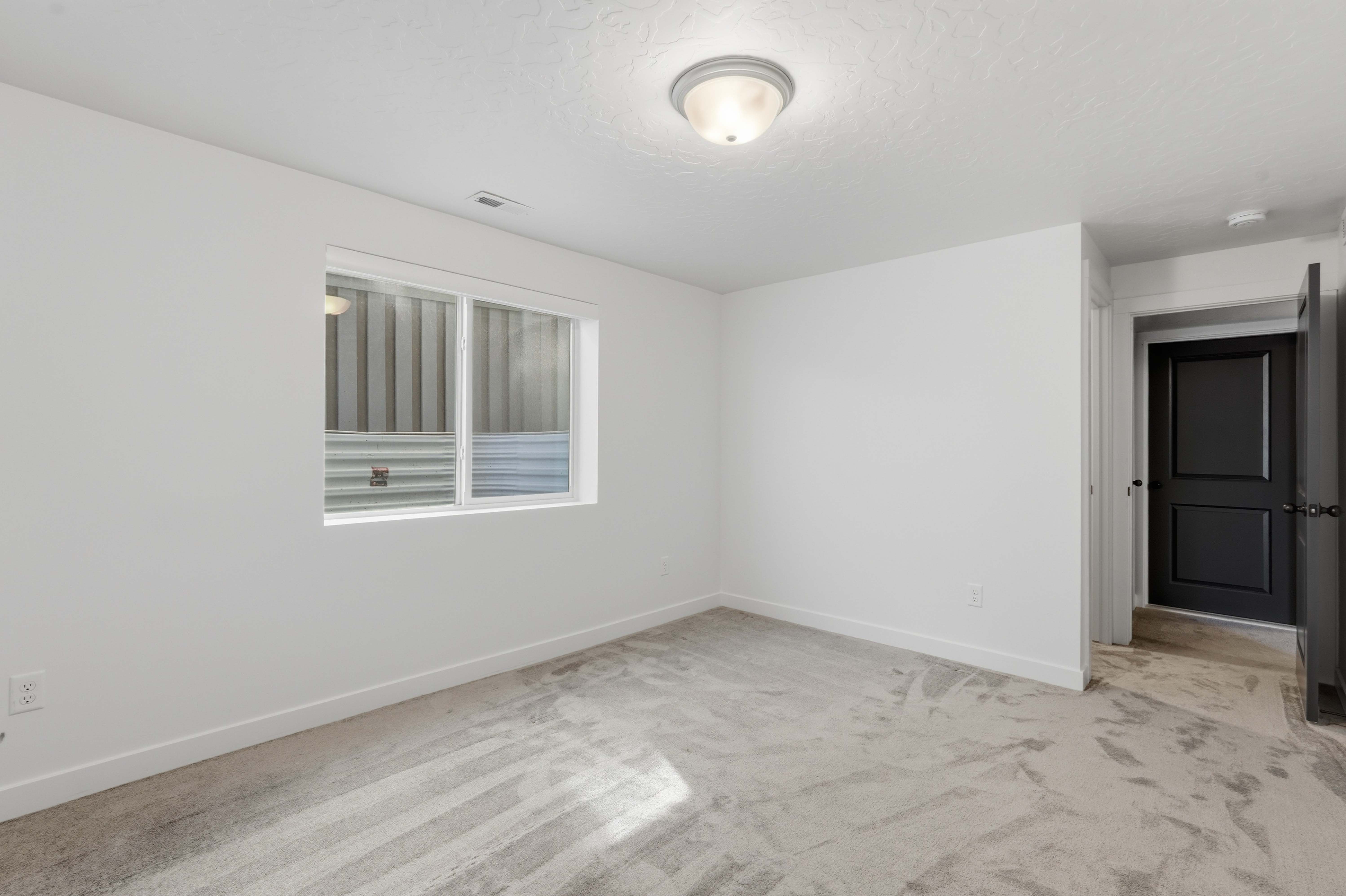 Room featuring light gray carpeting, crisp white walls, and a recessed window