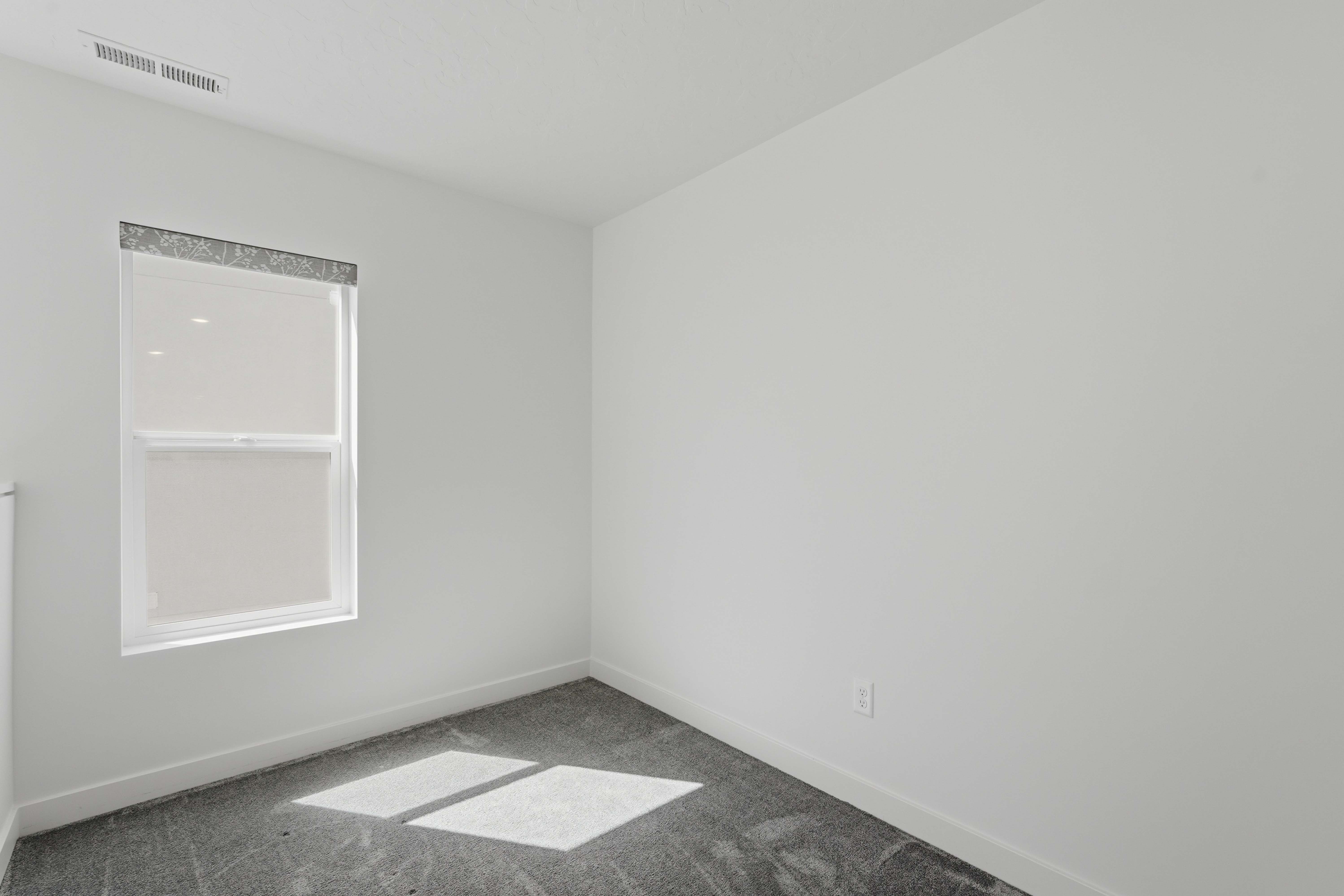 Bright room featuring neutral wall tones and a single window with a roller shade