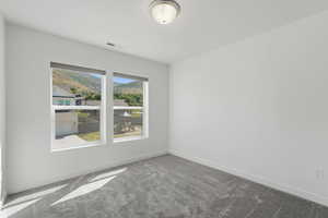 Bright interior space featuring two large windows, roller shades, white walls, gray patterned carpet, and a flush mount ceiling light
