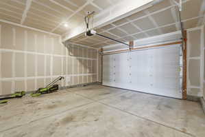 Spacious garage featuring a concrete floor, ceiling-mounted lighting, and an overhead garage door