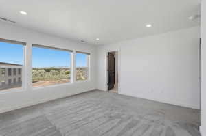 Spacious room featuring three large windows, recessed lighting, and grey patterned carpeting