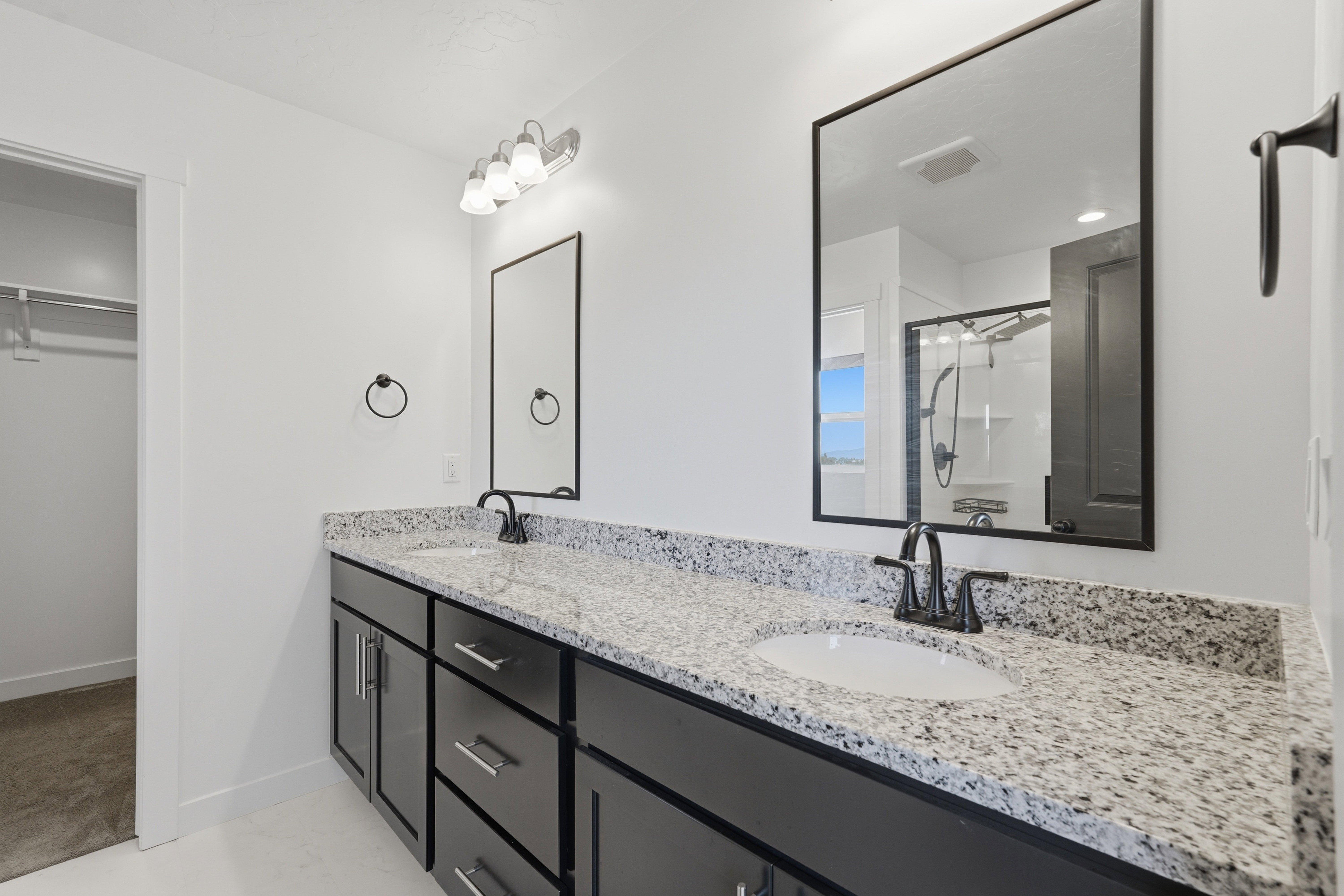 Dual vanity with granite-style countertop, undermount sinks, and dark cabinetry