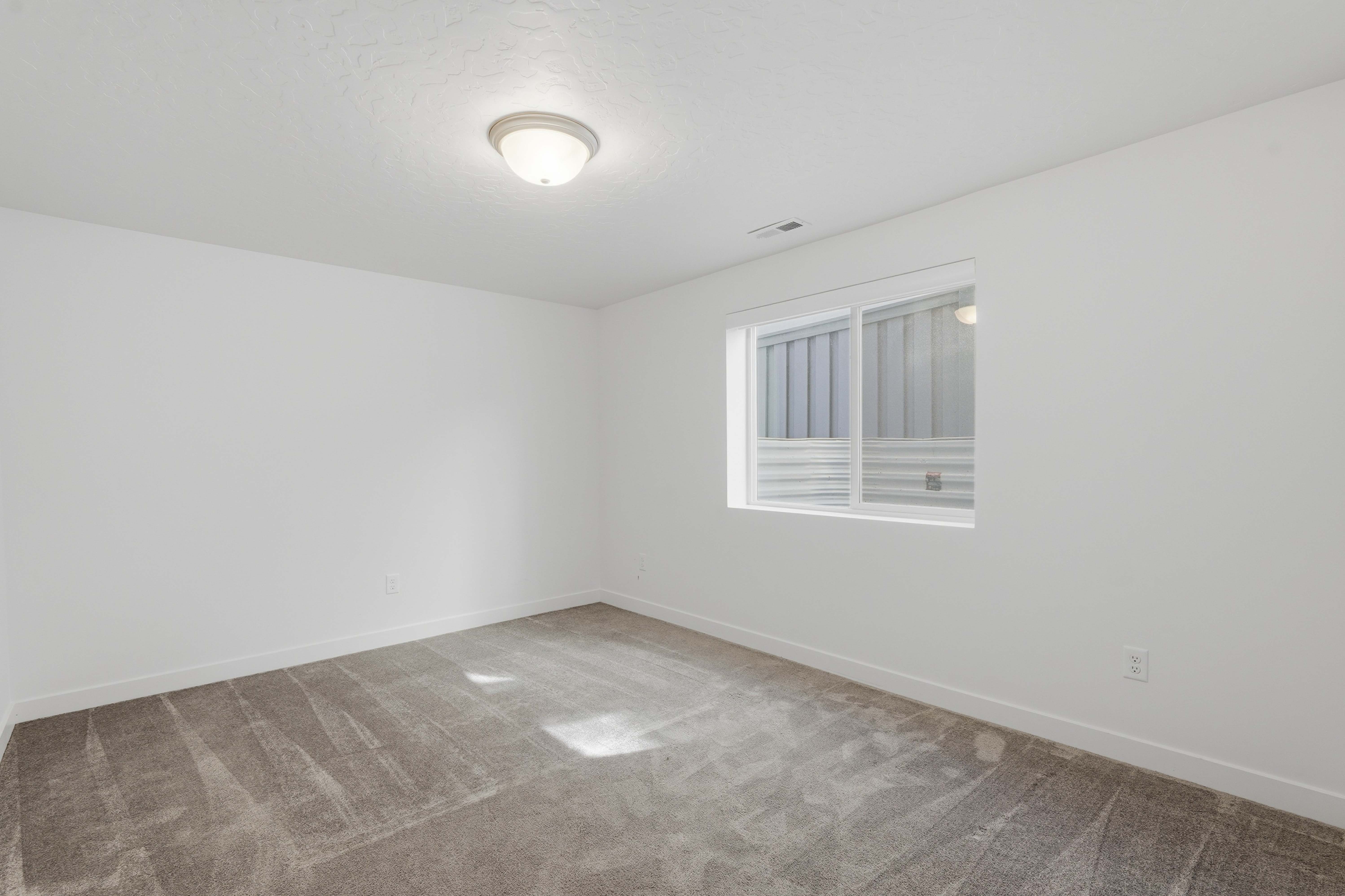 Room featuring neutral-toned carpet, white walls, and a white trim baseboard