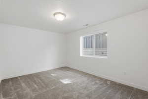 Room featuring neutral-toned carpet, white walls, and a white trim baseboard