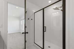 Walk-in shower with dark-framed glass enclosure, square rain shower head, and recessed lighting