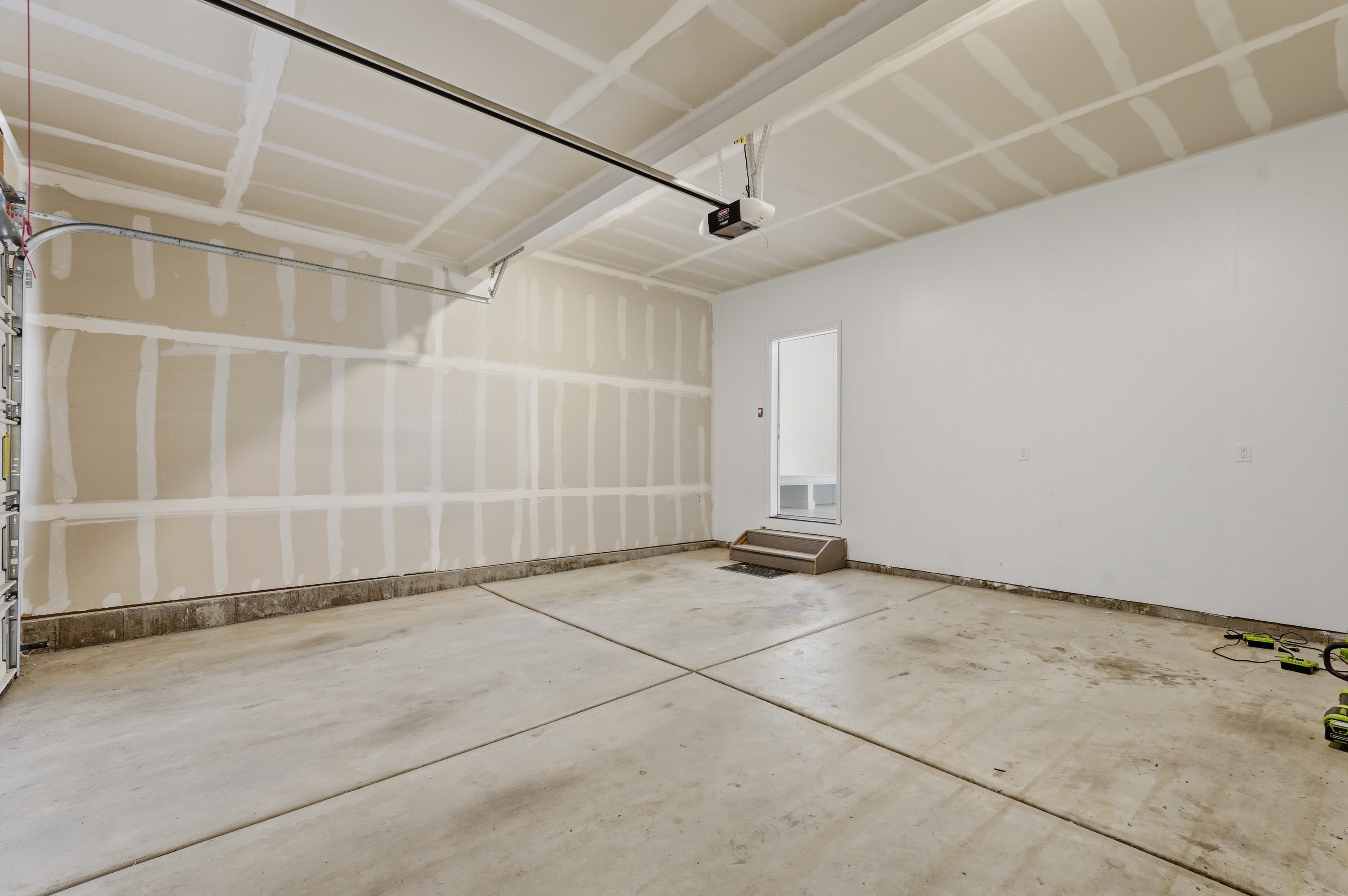 Spacious garage with concrete flooring, automatic garage door opener, and interior access door