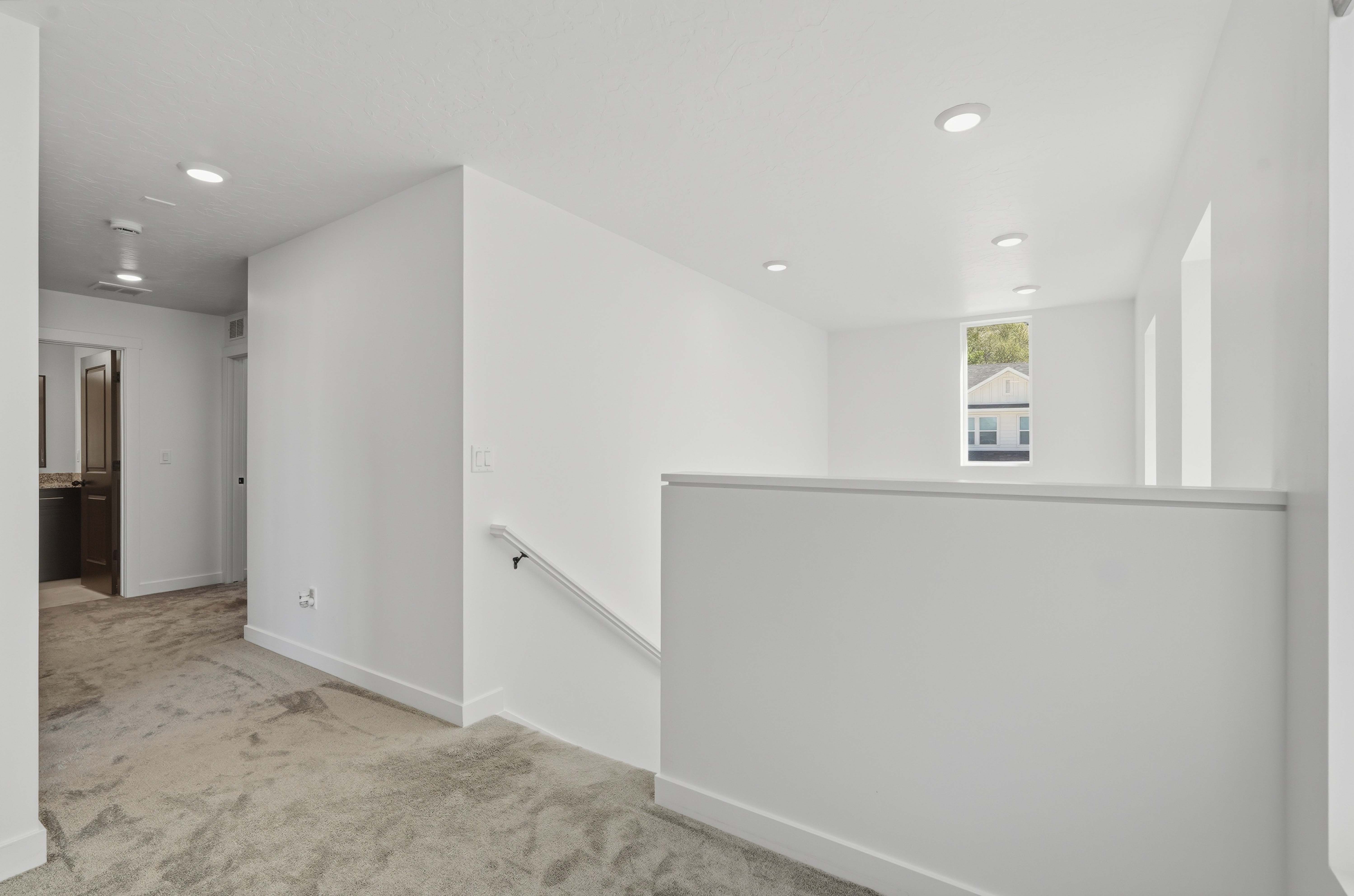 Upper level featuring a carpeted hallway, white walls, recessed lighting, and a window with exterior views