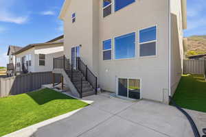 Rear exterior featuring a concrete patio and artificial turf areas