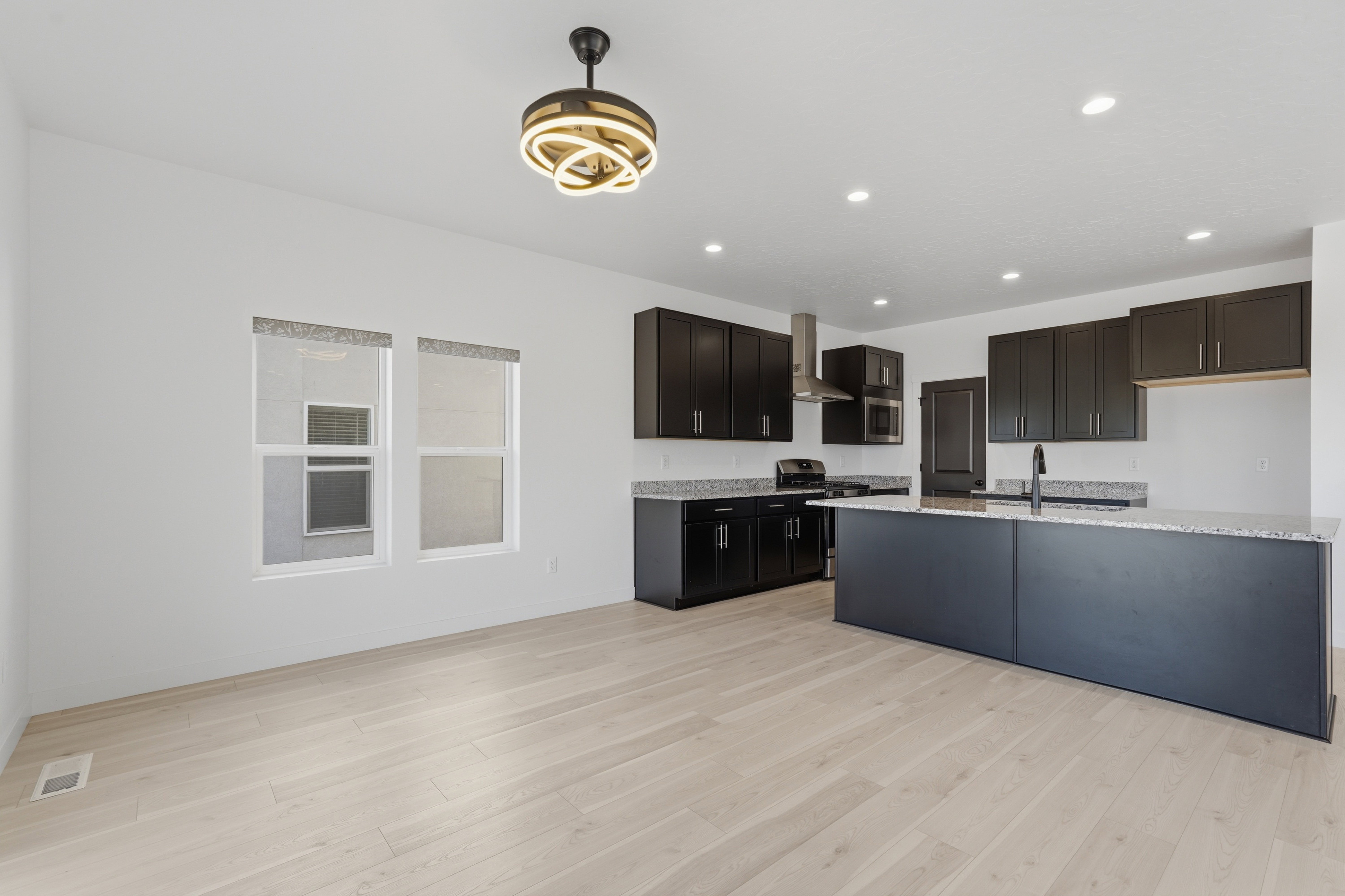 Open-concept kitchen and living area featuring light wood-finish flooring, white walls, and recessed lighting
