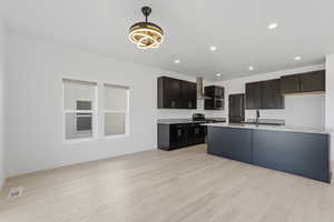 Open-concept kitchen and living area featuring light wood-finish flooring, white walls, and recessed lighting