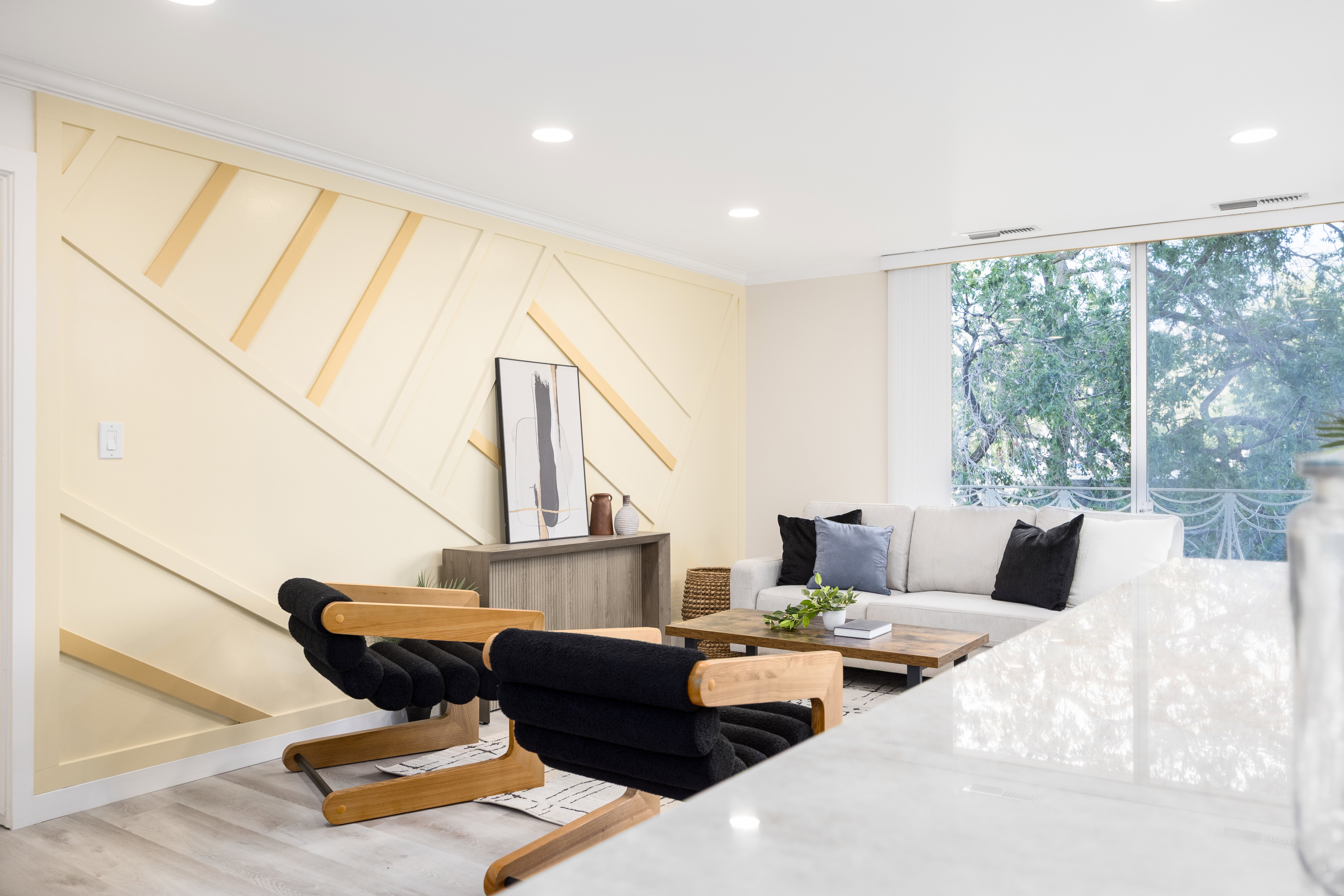 Living area featuring a geometric accent wall, recessed lighting, wood-finish flooring, and expansive windows