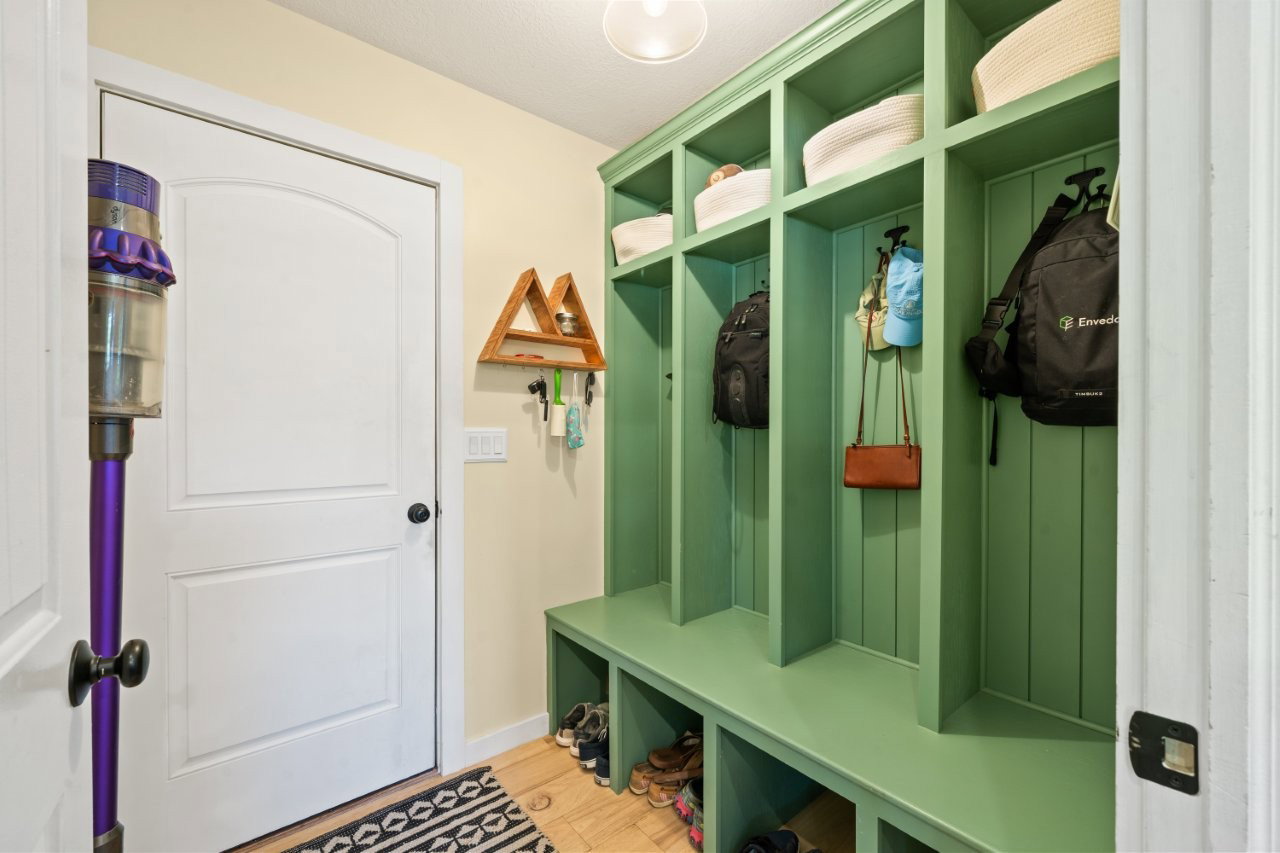 Built-in mudroom storage featuring individual cubbies, upper shelving, and a bench seating area