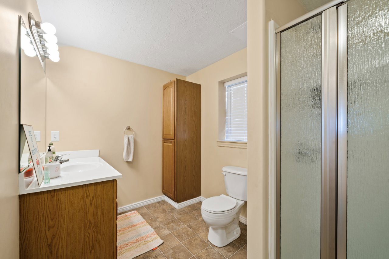 Bathroom featuring a wood-finish vanity with an integrated sink, white countertop, and a vanity mirror with a decorative light fixture