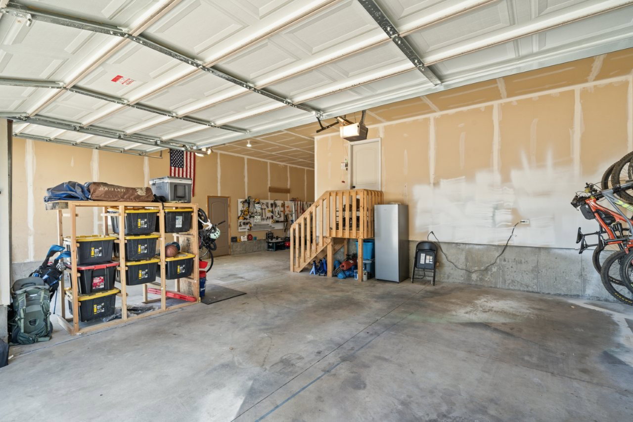 Spacious garage featuring a concrete floor, exposed ceiling joists, and a partial wood staircase