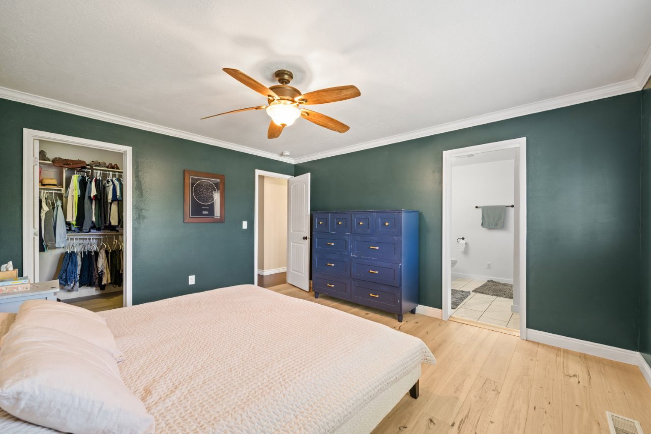 Bedroom featuring wood-finish flooring, a ceiling fan with integrated lighting, and crown molding