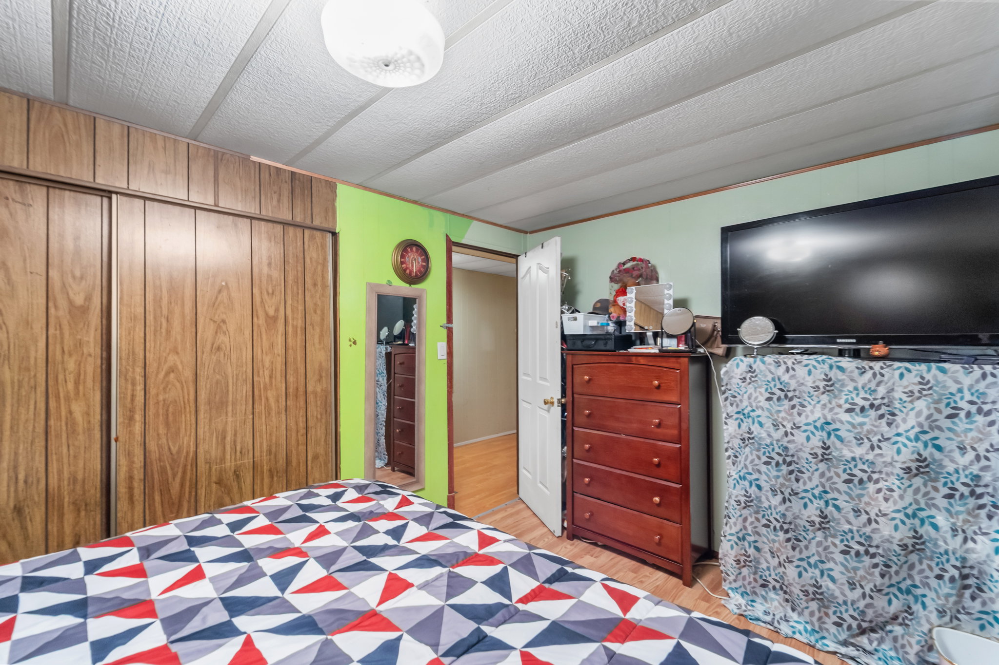Interior room with wood-finish sliding closet doors, light green and bright green painted walls, and wood-finish flooring