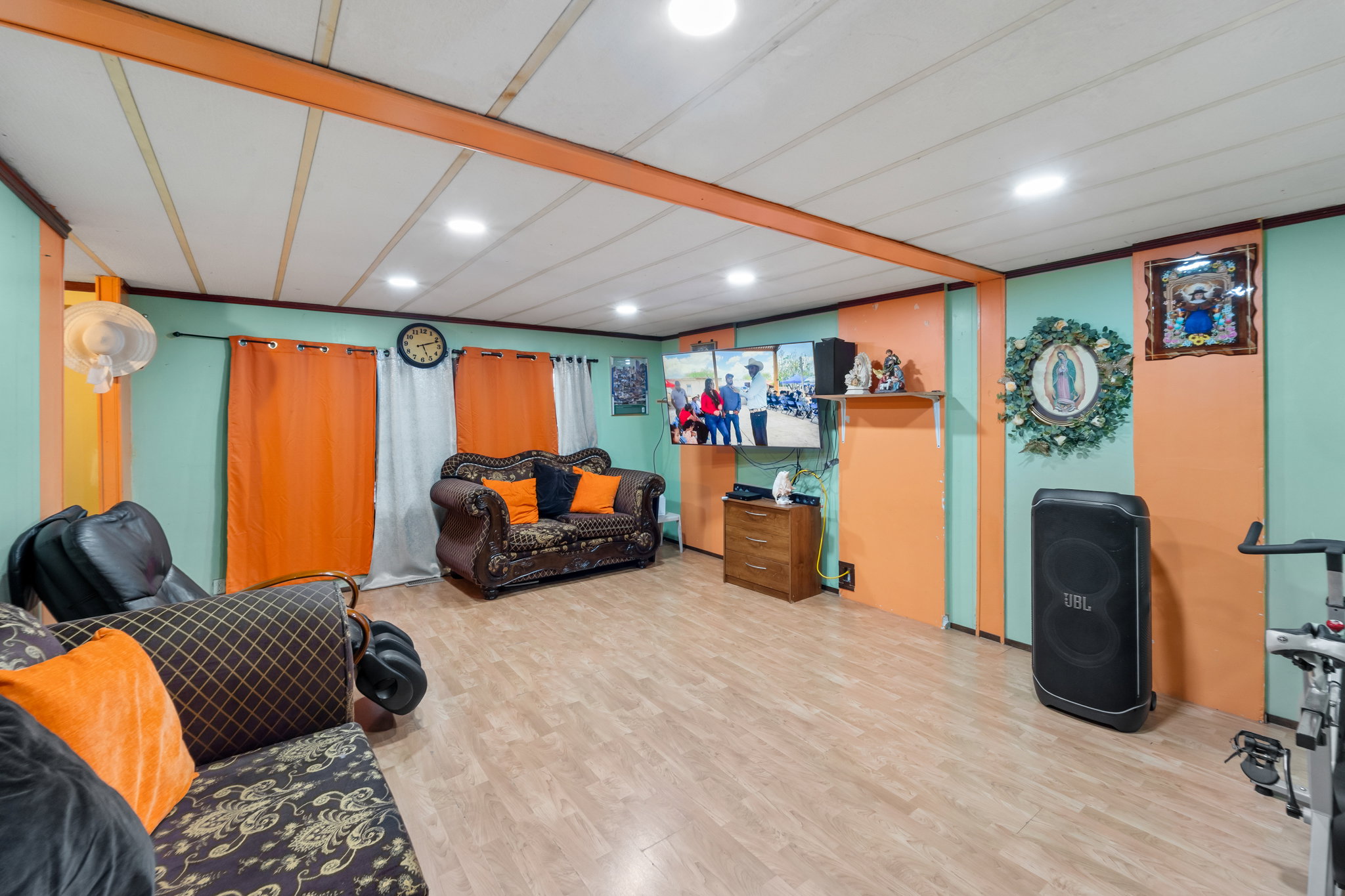 Spacious room featuring wood-finish flooring, recessed ceiling lighting, and exposed ceiling beams