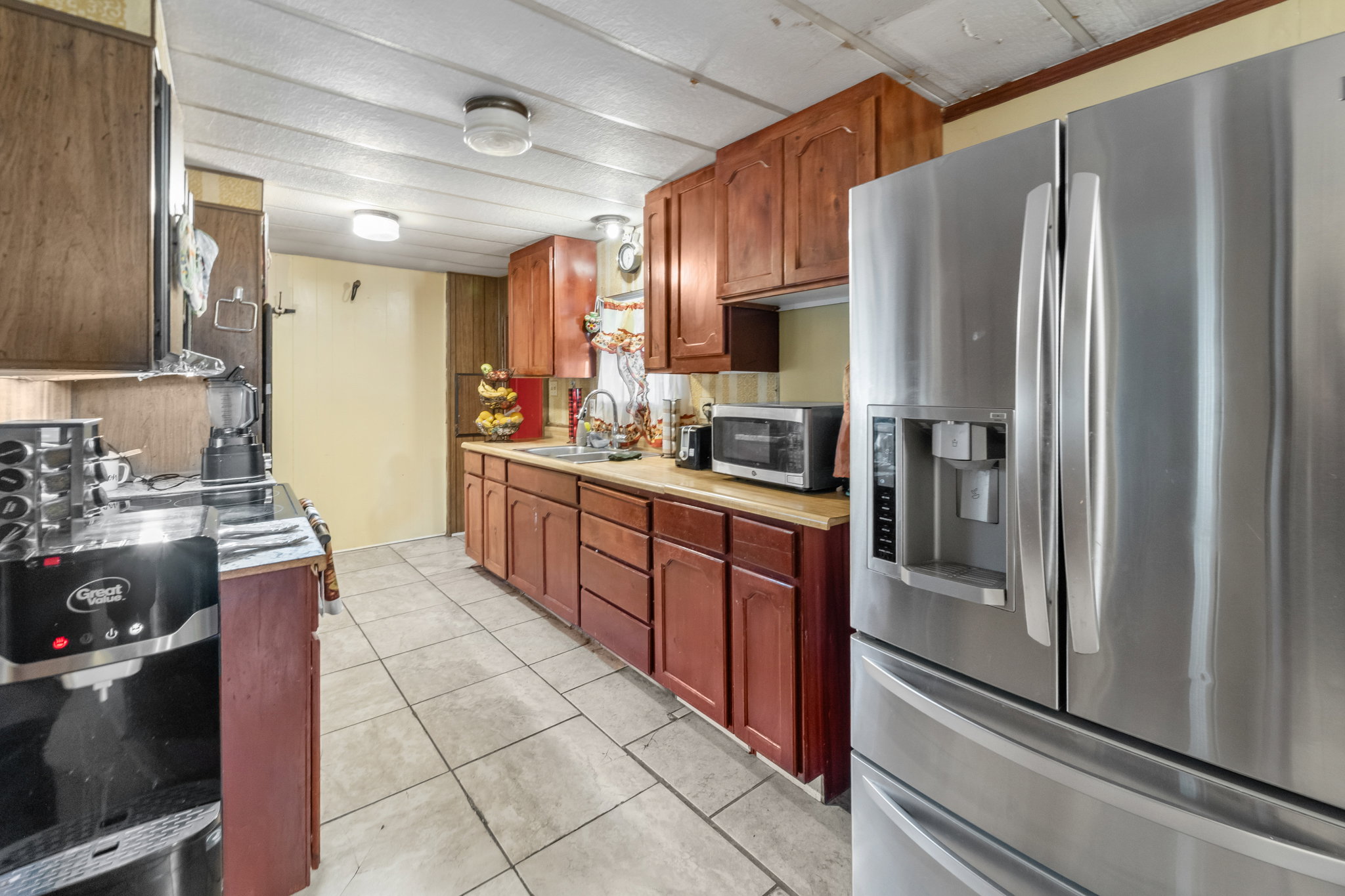 Kitchen featuring recessed panel wood cabinetry, wood-finish countertops, and tile flooring