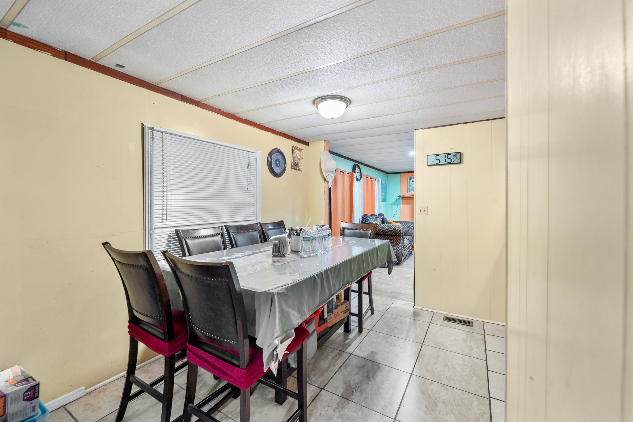 Tiled flooring extends through this room, featuring a window with blinds, light-toned walls, and a panel ceiling
