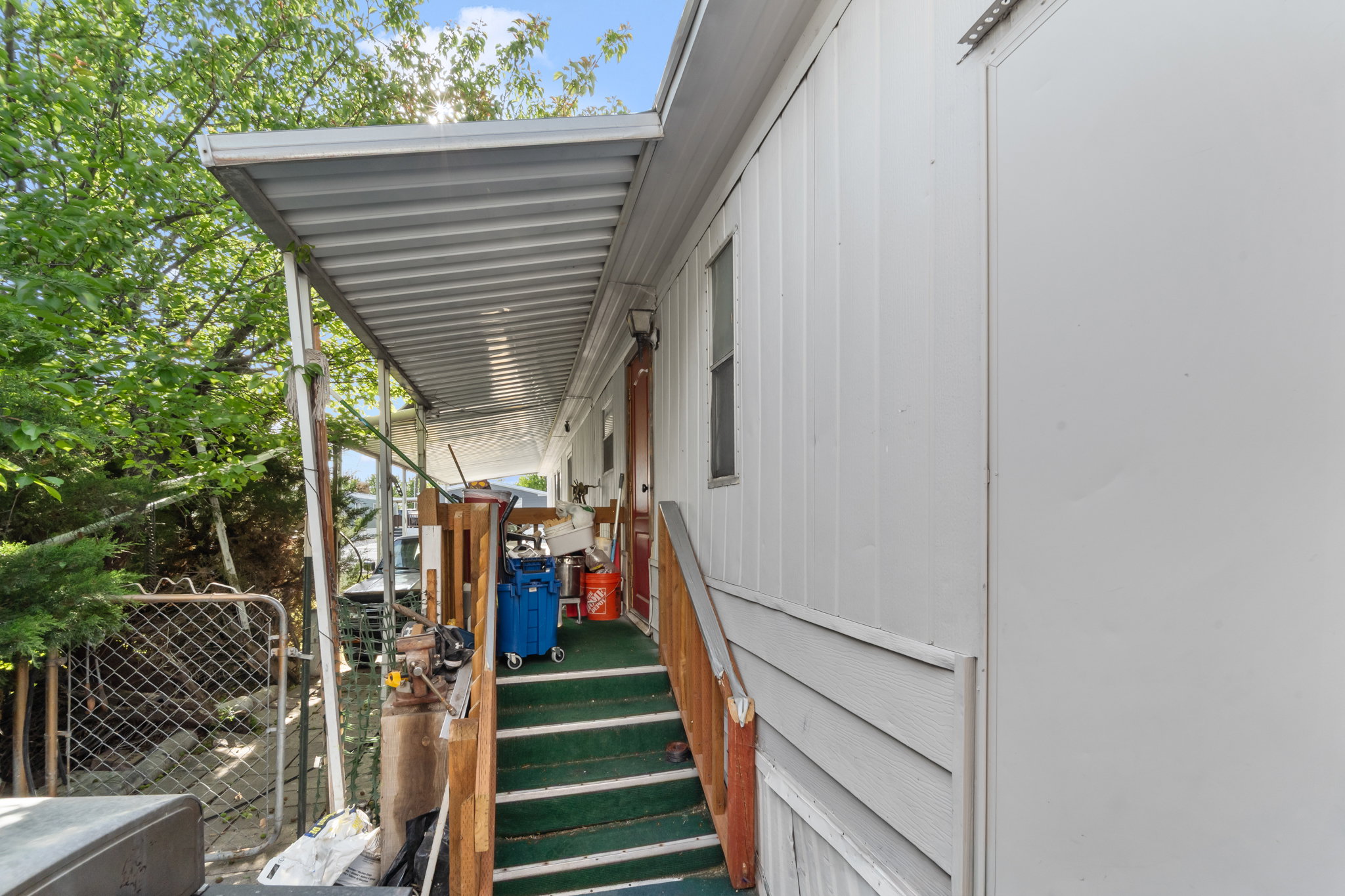Covered porch with metal roofing, wood railing, and carpeted steps
