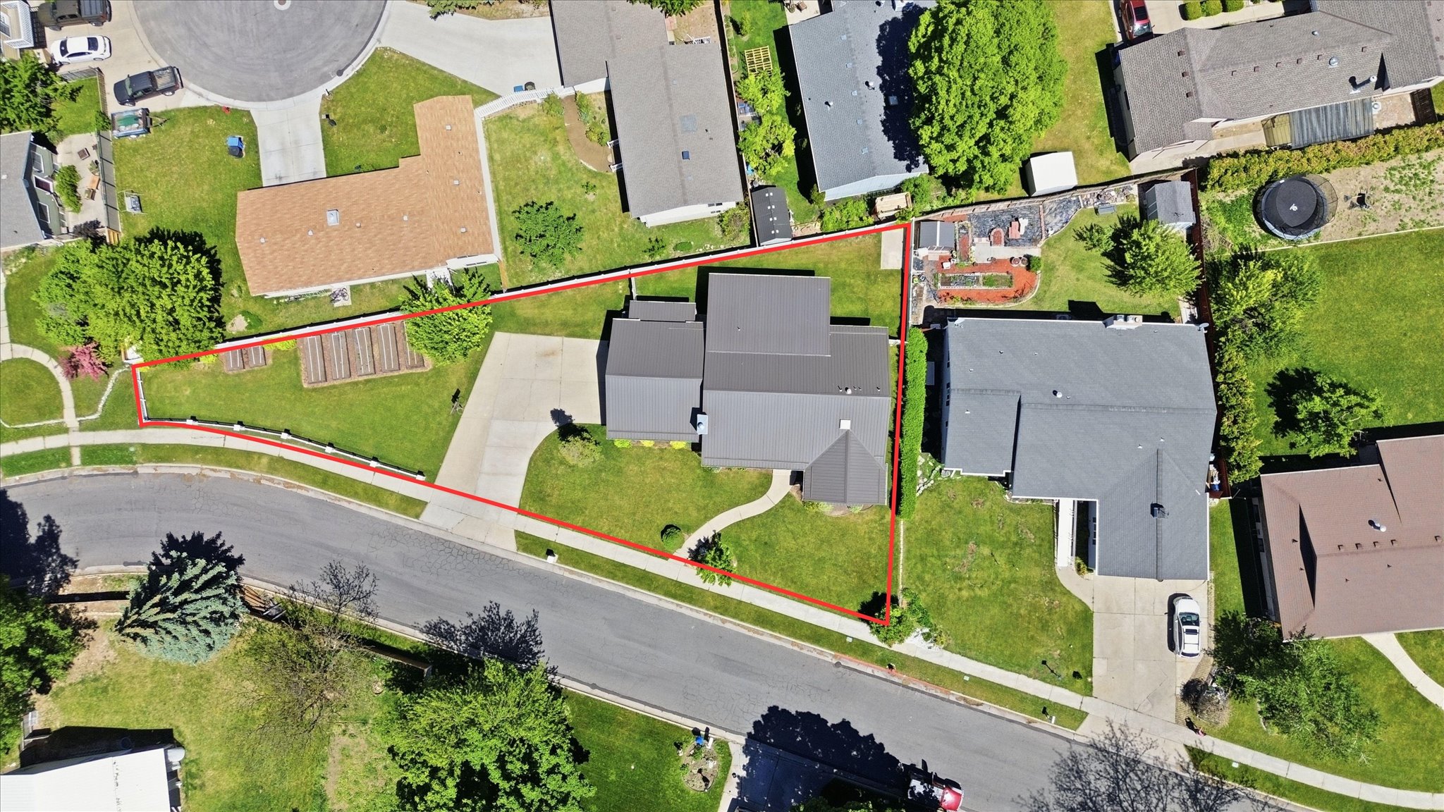 Aerial perspective showcasing a residential property with a dark-pitched roof and light-toned driveway