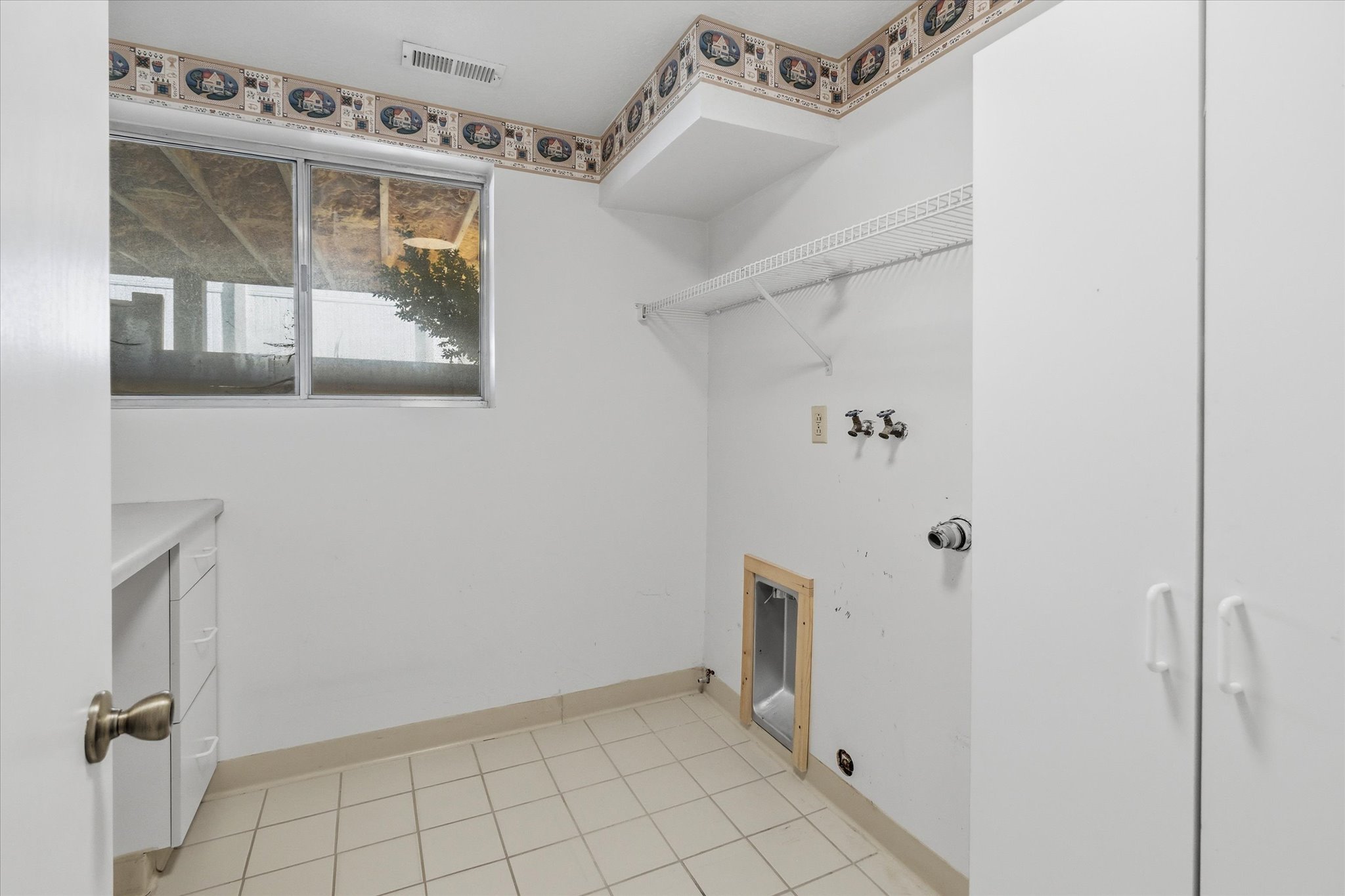 Laundry area featuring tile flooring, a window, built-in cabinetry, shelving, and appliance hookups