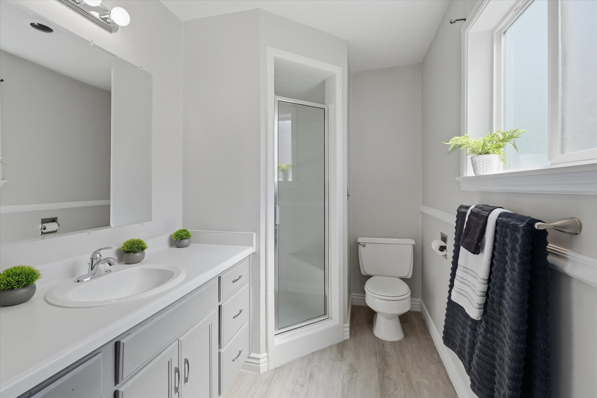Primary Suite Bathroom featuring a vanity with an integrated sink, polished chrome faucet, and gray cabinetry with step-inshower