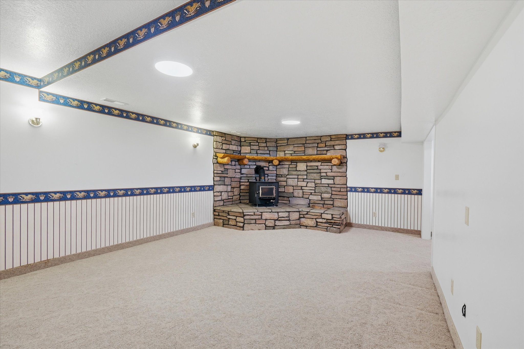 Spacious room featuring a stone-clad fireplace with a wood-burning stove and a log mantel