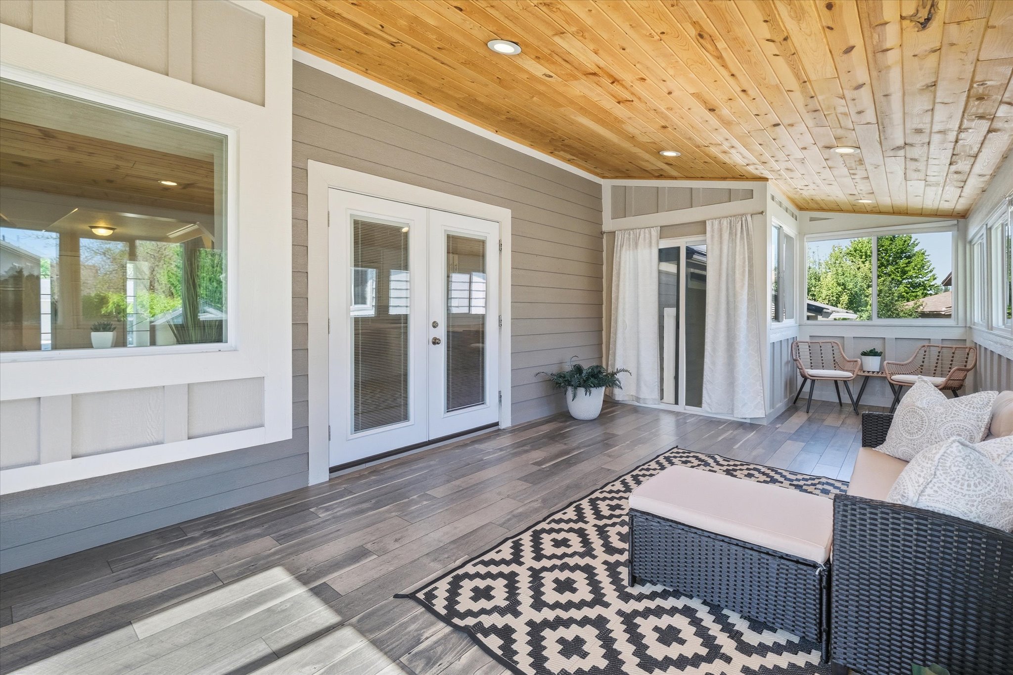 Enclosed Sunroom living area featuring a natural wood-finish plank ceiling with recessed lighting