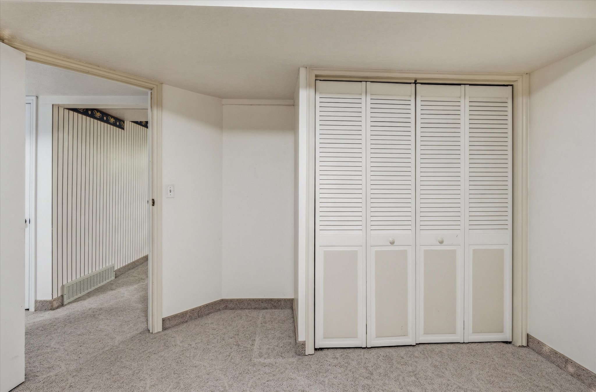 Den Room featuring louvered bi-fold closet doors, light-toned carpeting, and white painted walls