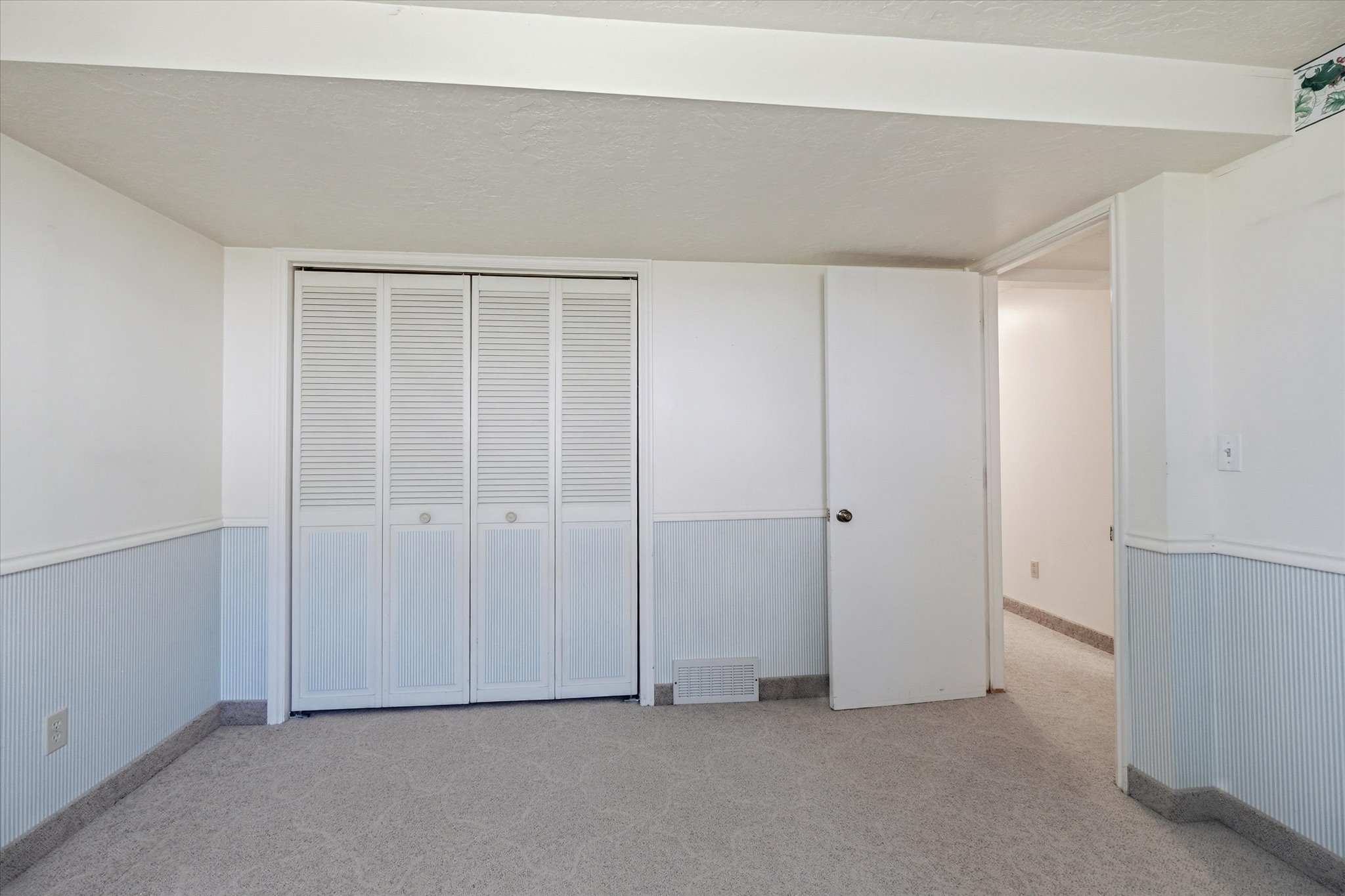 Interior room featuring carpeting, light blue wainscoting, and white walls