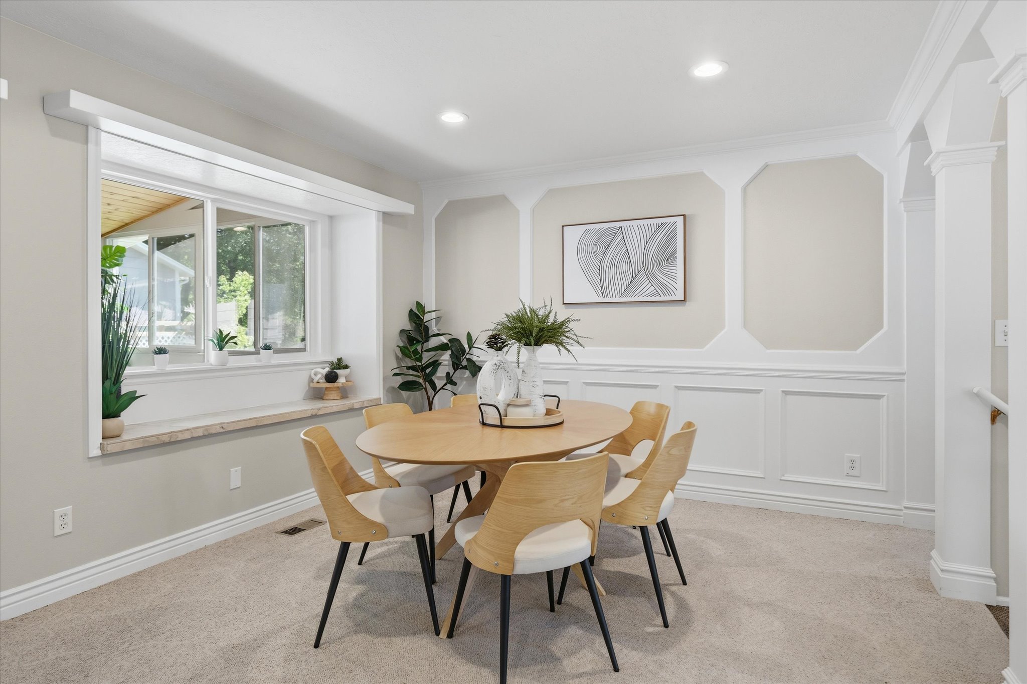 Dining area featuring a large window with a deep sill, detailed wall paneling, crown molding, recessed lighting, and soft carpeting
