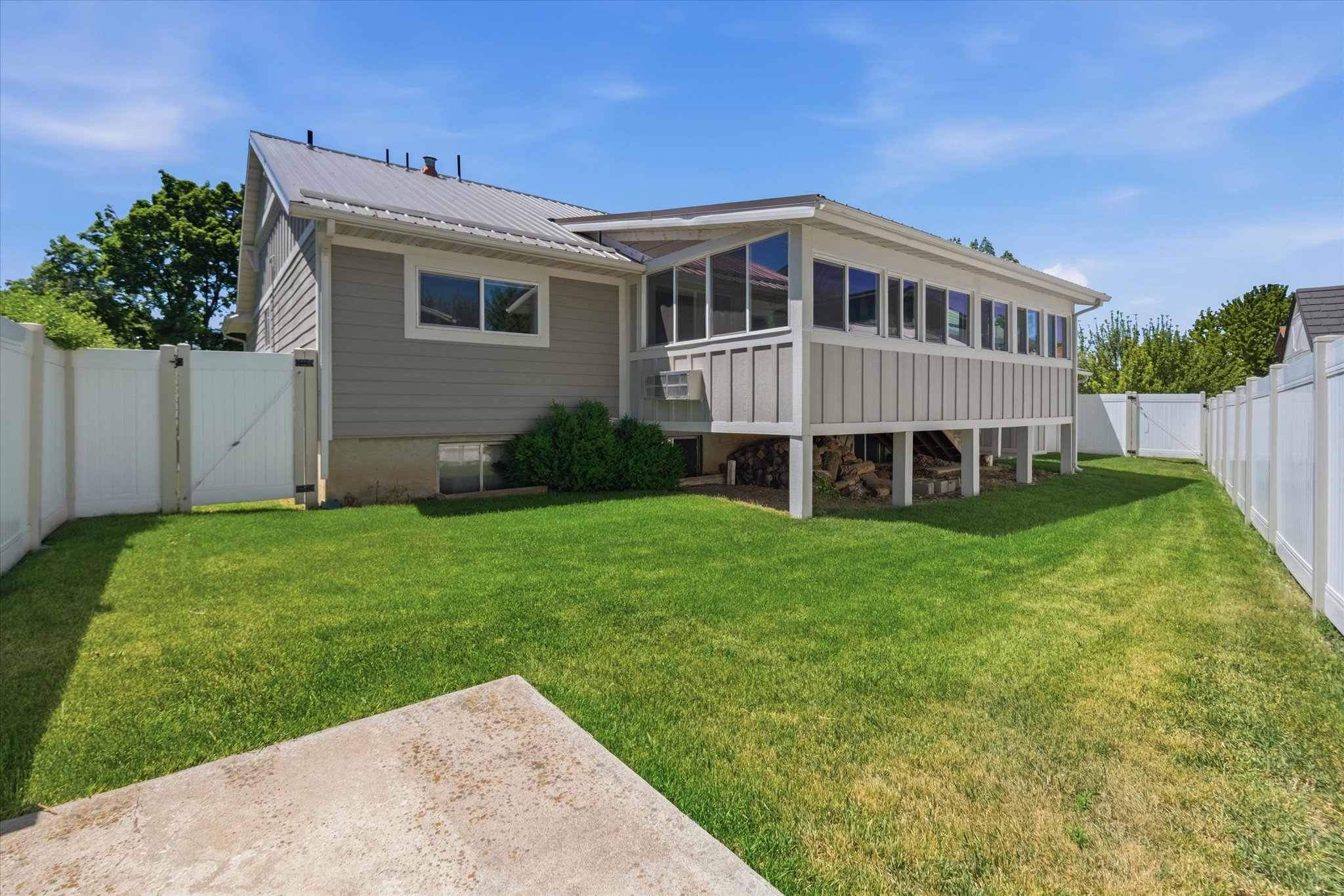 Rear exterior featuring a sunroom, metal roof, and a fenced backyard