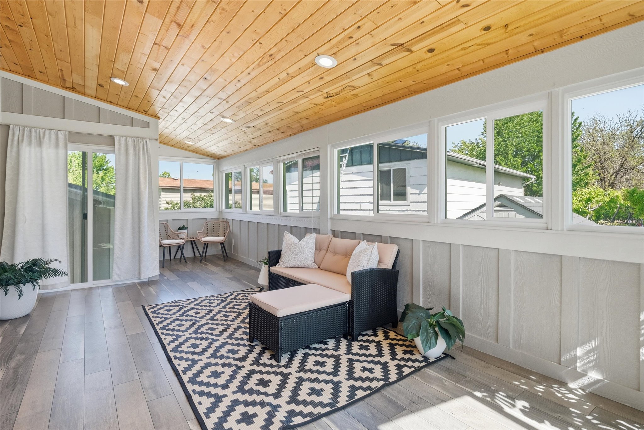 Sunlit room featuring a natural wood-finish plank ceiling with recessed lighting