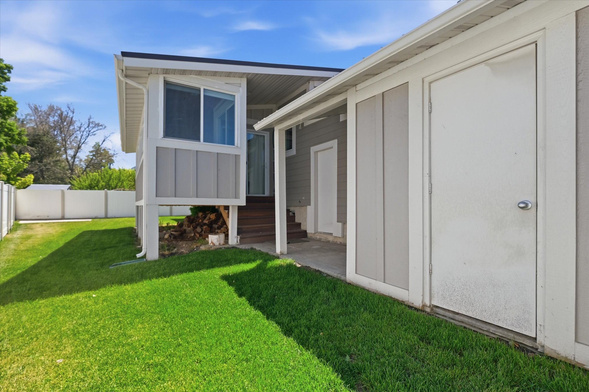 Exterior featuring a covered patio, enclosed storage space, raised deck/sunroom, and a fenced backyard with established landscaping