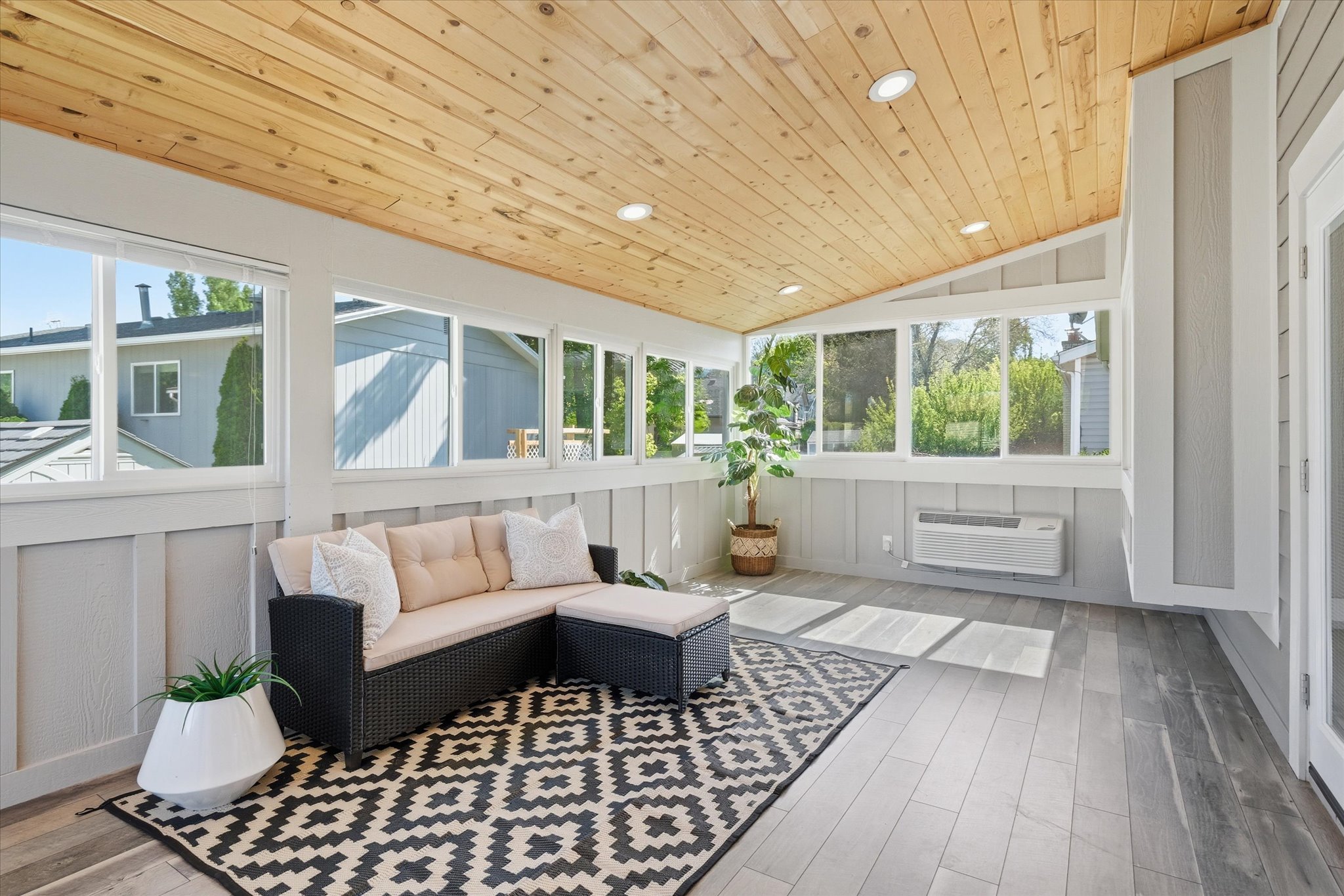 Bright sunroom featuring a natural wood-finish vaulted ceiling with recessed lighting