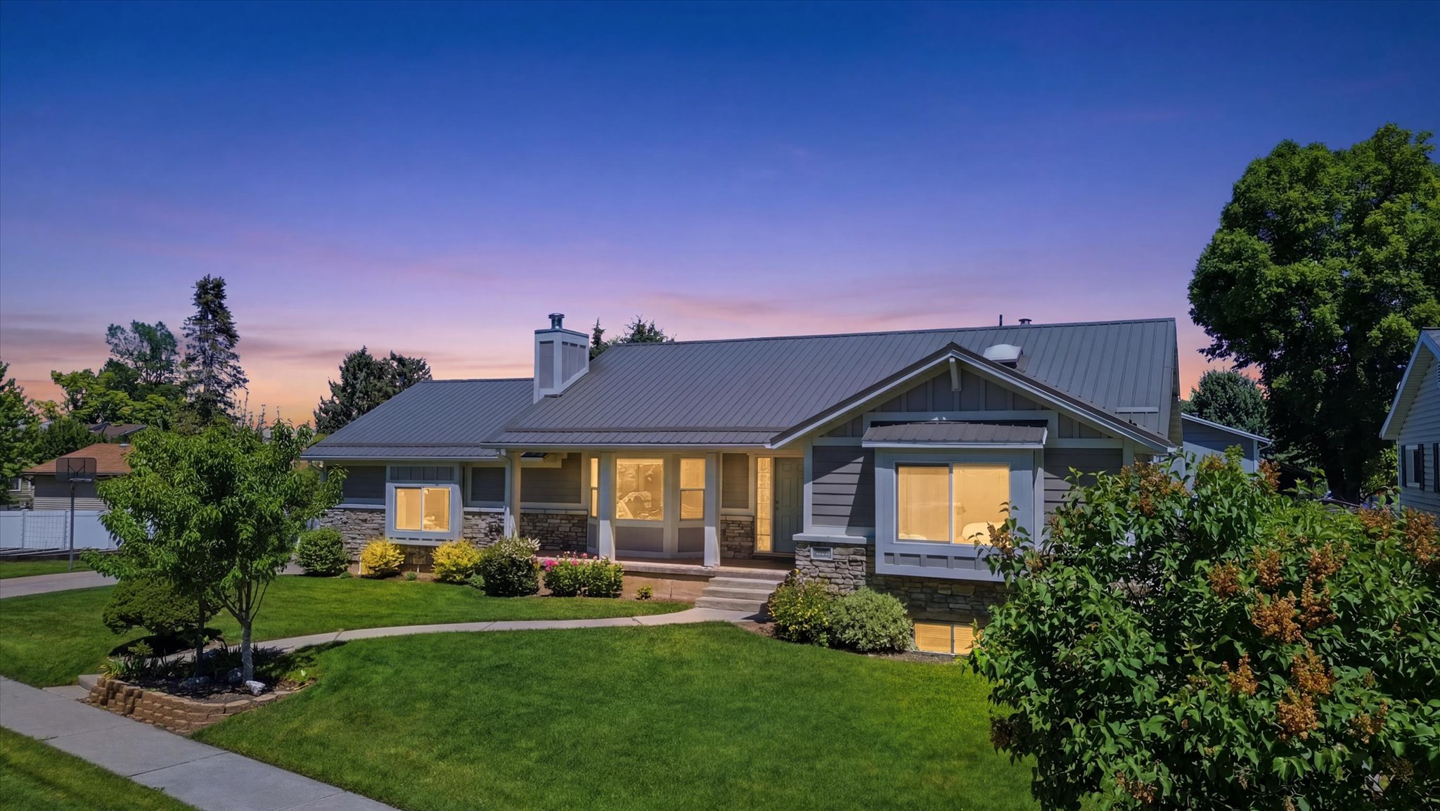 Split-level residence featuring a metal roof, stone accents, and composite siding