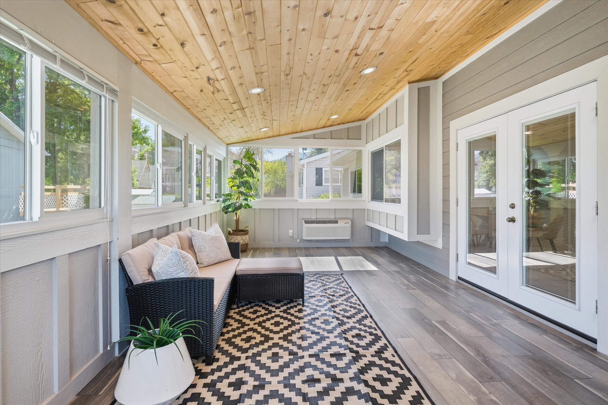 Enclosed sunroom porch featuring wood-finish flooring, a natural wood paneled ceiling with recessed lighting, and multiple windows